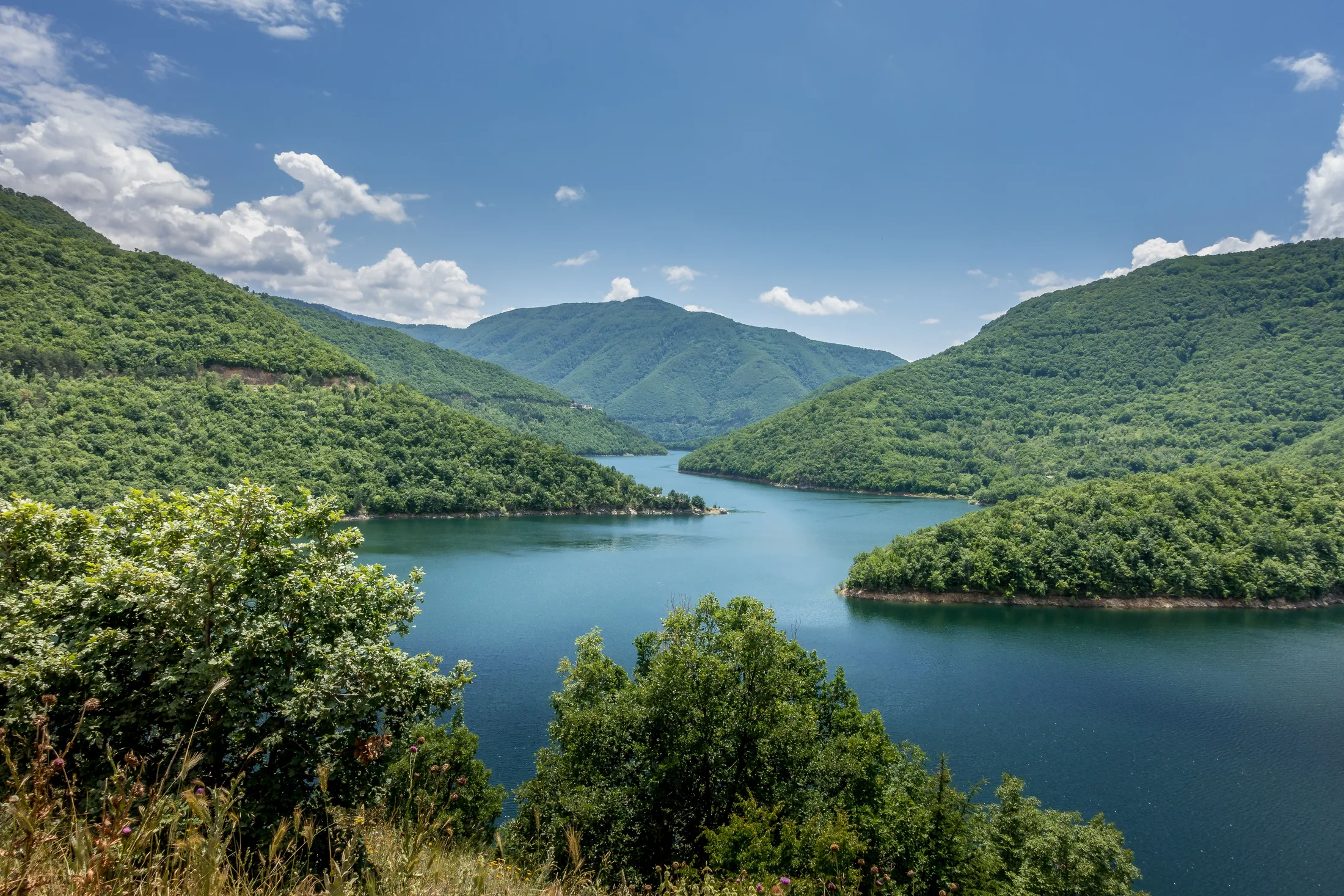Stausee zwischen bewaldeten Bergen in den bulgarischen Rhodopen